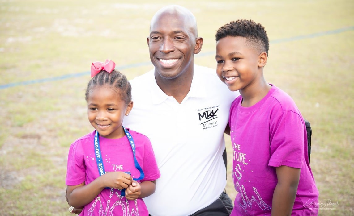 Wayne Messam taking a picture with cute kids.